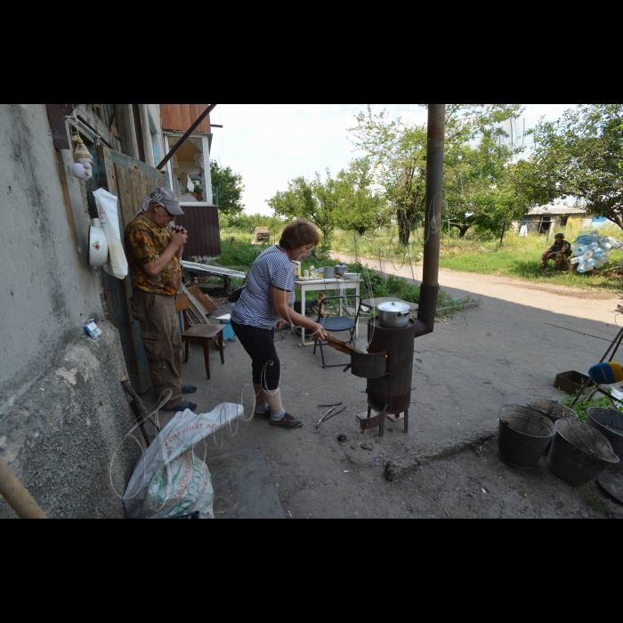 6 липня 2015. Зона АТО. Донецька область, селище Піски. Клуб розбитий вщент. Церква теж пошкоджена так, що будувати її потрібно заново. Біля одного будинку на вулиці стоїть буржуйка. Жінка середніх років готує вареники. Ще один чоловік сидить поруч і постійно курить. Показує курей, яких тримає у темному підвалі будинку у металевій клітці. Кури живуть у темниці. Так люди зберігають їм життя. Олена розповідає, що у їх кварталі зараз живе чотири людини. А взагалі у Пісках, за її підрахунками – 20 чоловік і багато собак. А у мирний час населення селища складало до 5 тисяч.

Жителька Пісків Олена готує вареники біля свого будинку